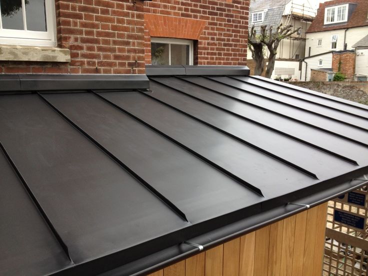 a black metal roof is shown in front of a brick building