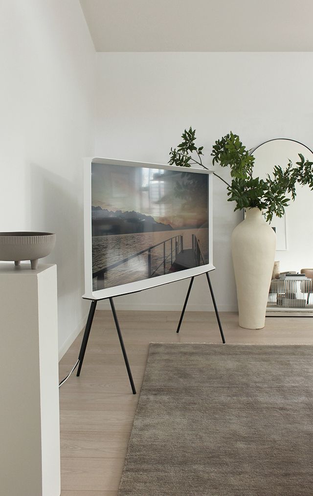 a television sitting on top of a wooden stand next to a vase filled with plants