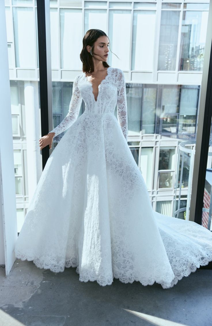 a woman wearing a white wedding dress standing in front of a window