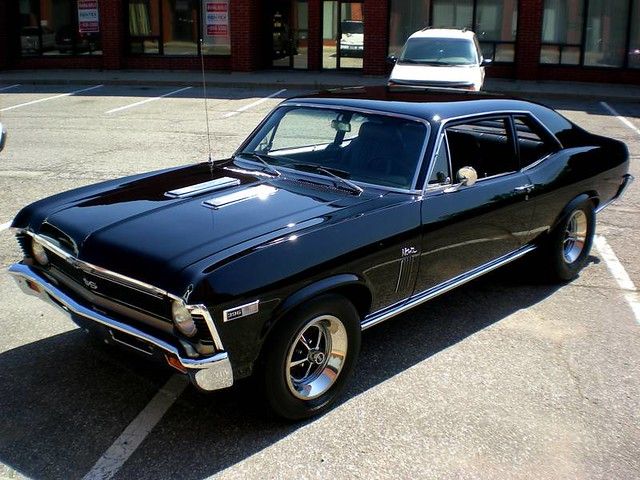 an old black muscle car parked in a parking lot