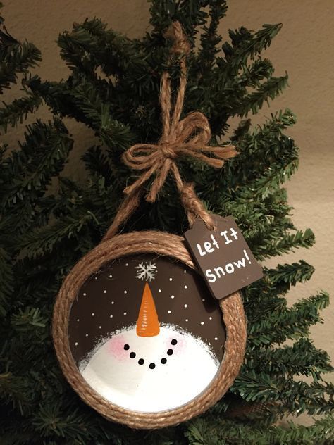 a snowman ornament hanging from a christmas tree with a tag that says let it snow