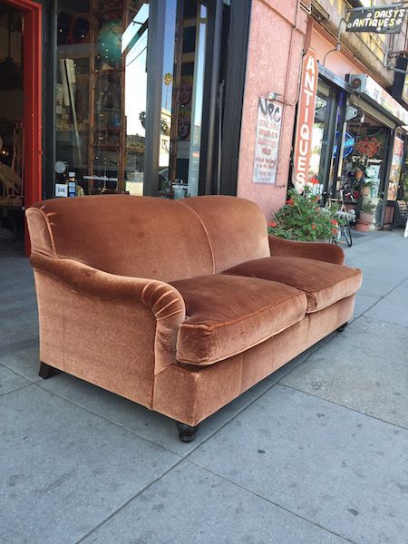 a brown couch sitting on top of a sidewalk