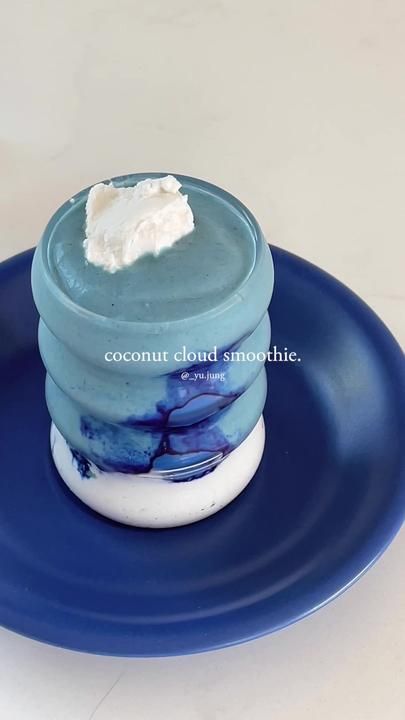 there is a blue plate with three small containers on it that have whipped cream in them