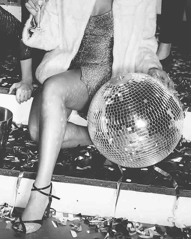 a woman sitting on top of a table next to a disco ball