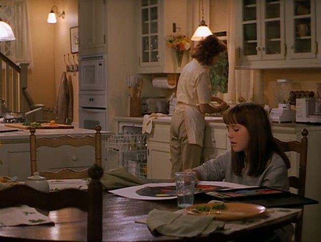 two women are in the kitchen preparing food for dinner, and one woman is on the counter