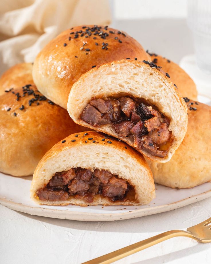 three rolls filled with meat on top of a white plate