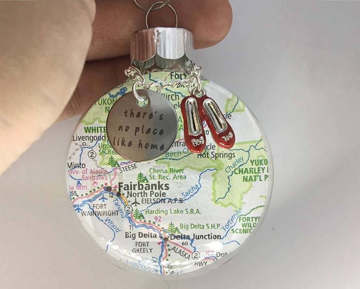 a hand holding a glass ornament with two pairs of scissors in the shape of a map