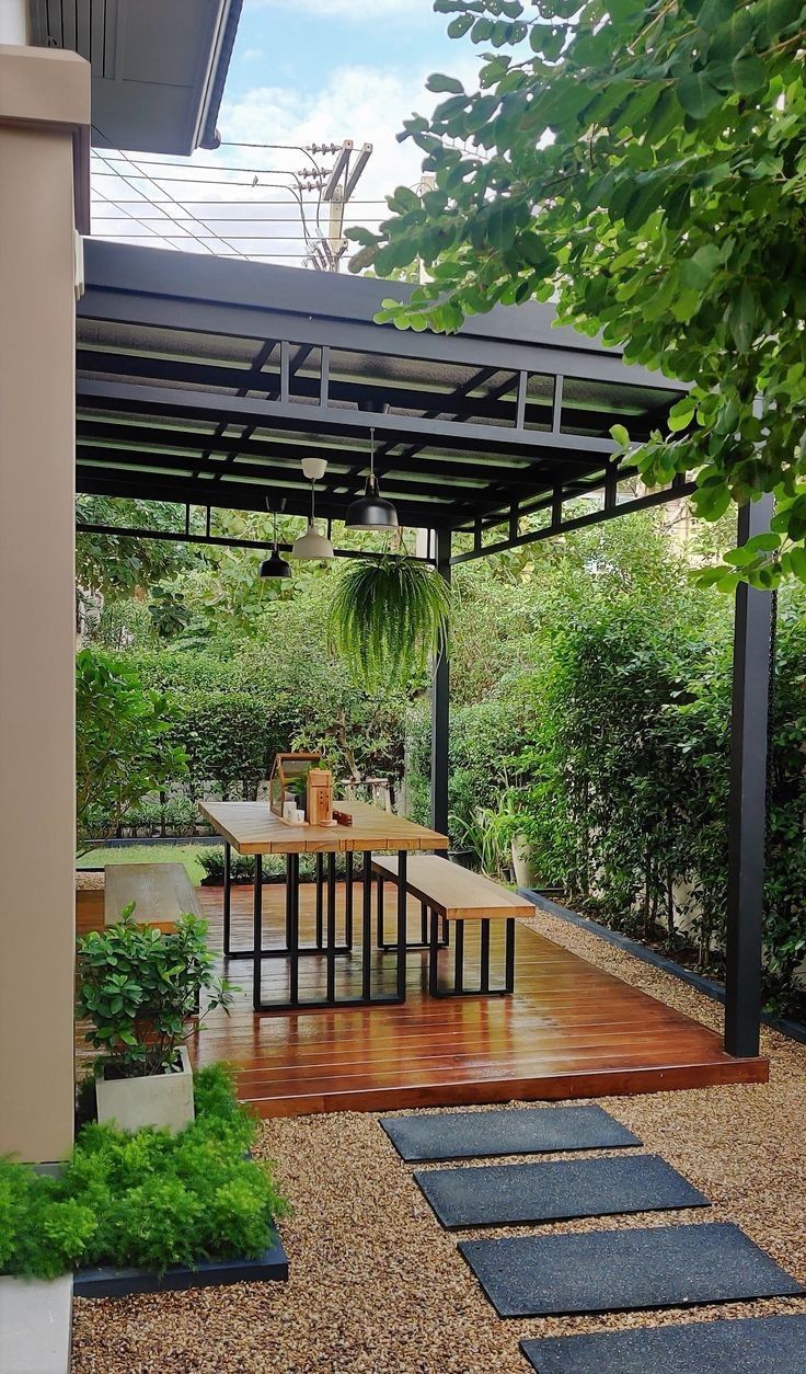 an outdoor dining area with wooden tables and chairs, surrounded by greenery in the background