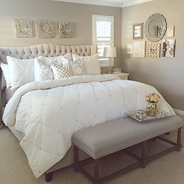 a white bed sitting in a bedroom next to a window with pictures on the wall