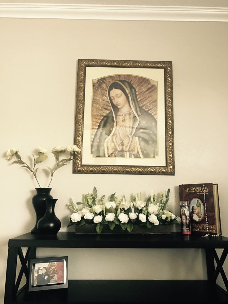 a black table topped with white flowers next to a framed painting and vase filled with flowers