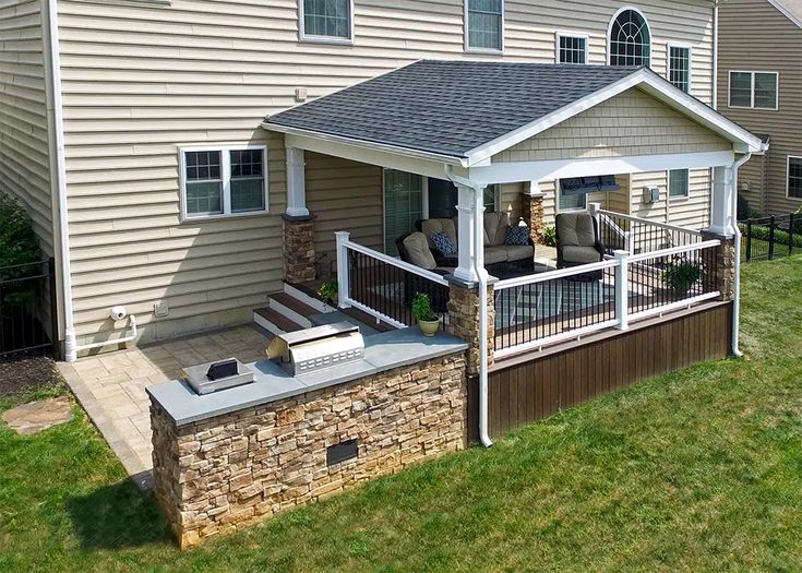 a house with a covered patio in front of it and an attached hot tub on the deck