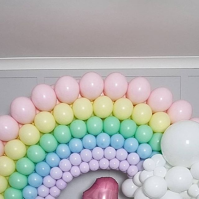 a pink flamingo balloon sitting on top of a table next to balloons in the shape of a rainbow