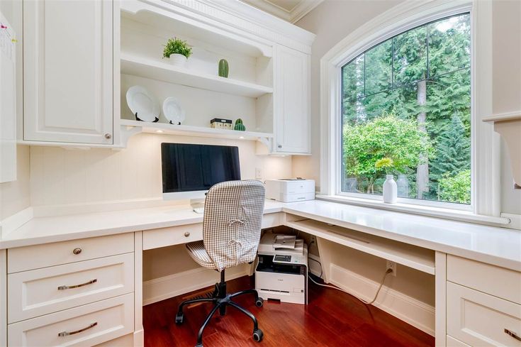 a desk with a computer on top of it in front of a window and wooden floors