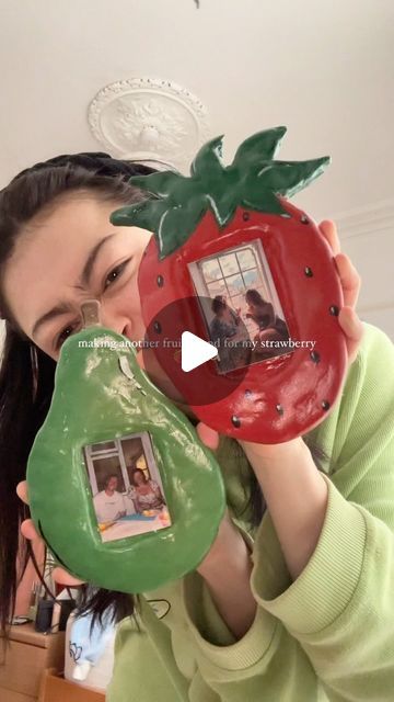 a woman holding up a red and green object in front of her face with the image of a strawberry on it