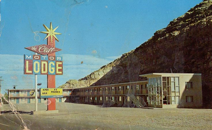 an old motel sign in front of a mountain