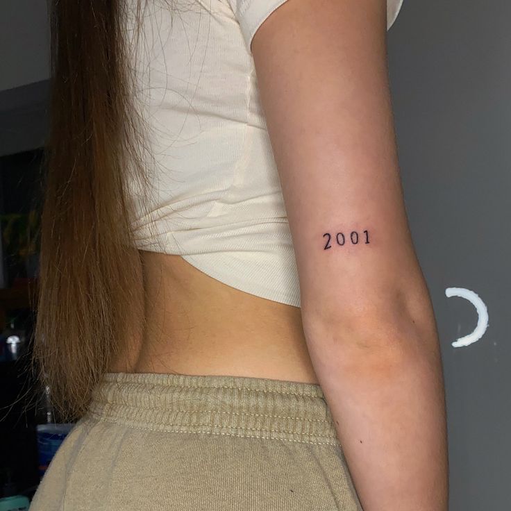 a woman with a small tattoo on her left arm and the number 2000 written in it