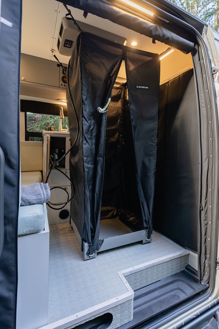 the interior of a van with two black curtains open and an electric outlet plugged in