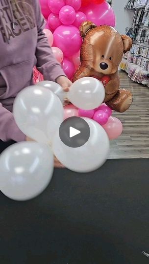 a person holding balloons in front of a teddy bear