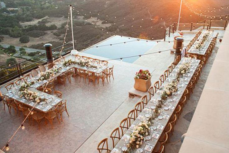 an outdoor dining table set up on top of a building with mountains in the background