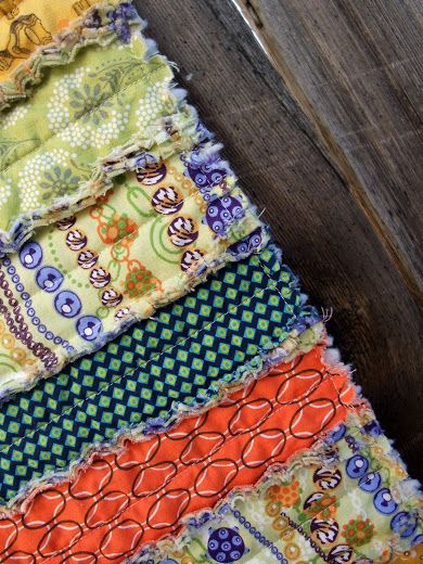 an assortment of different colored fabrics on a wooden surface