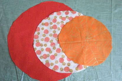 three pieces of fabric on top of each other with orange and white circles around them