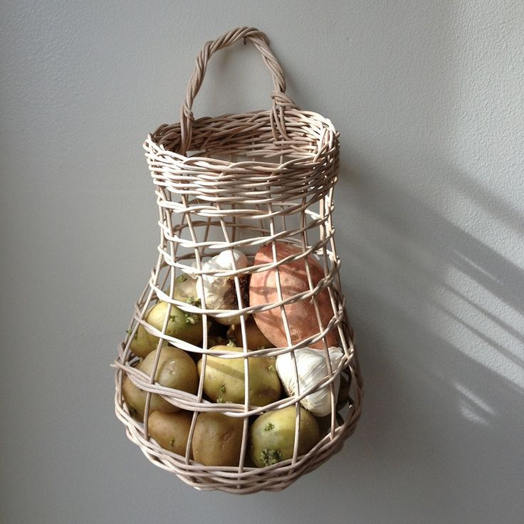 a basket filled with apples sitting on top of a white wall next to a window