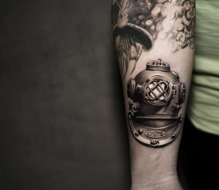 a man's arm with a diving helmet tattoo on it