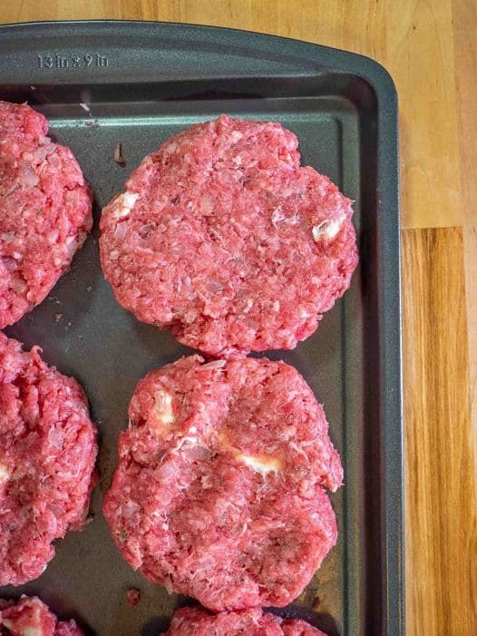 four hamburger patties on a baking tray ready to be cooked