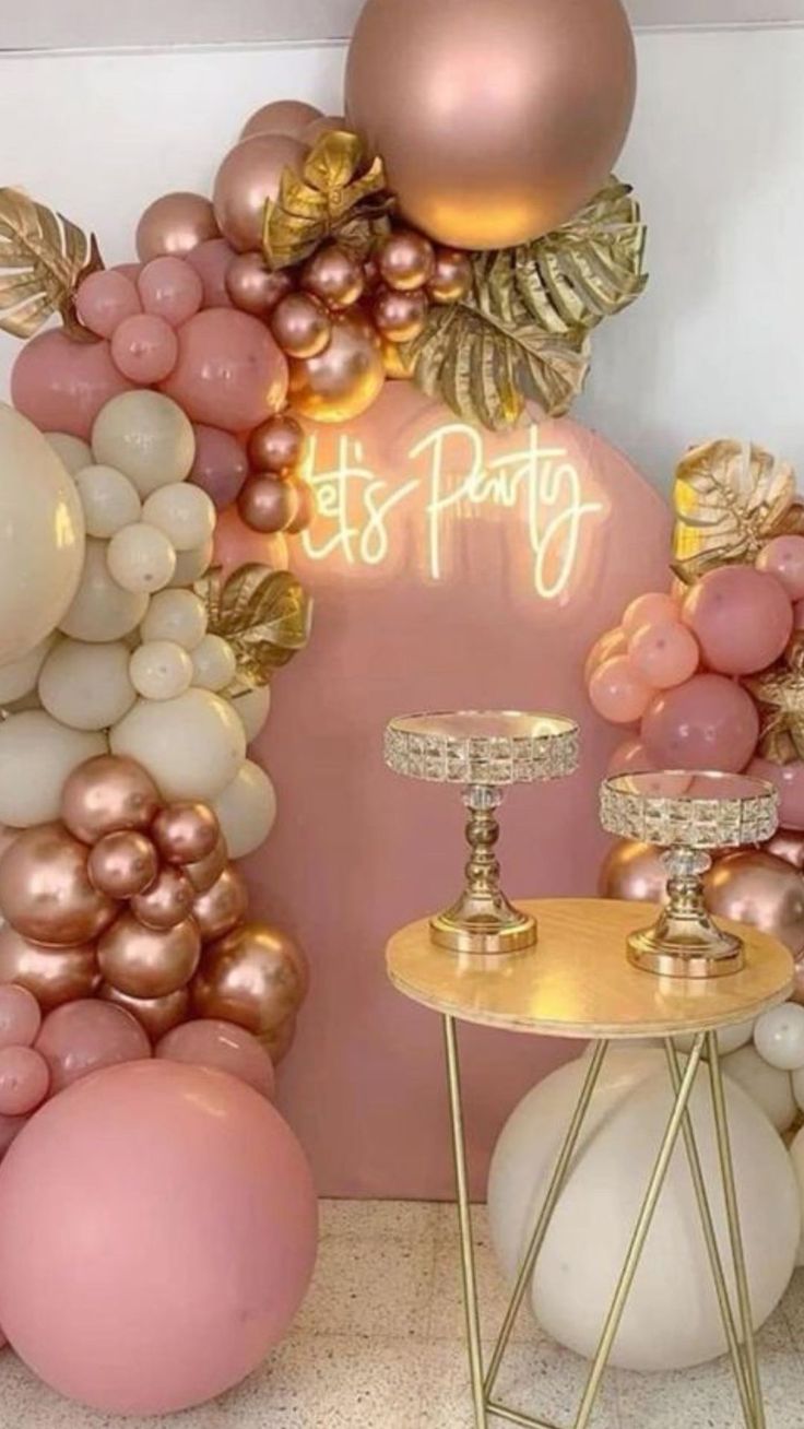 balloon arch with pink, gold and white balloons in the shape of letters that say it's party