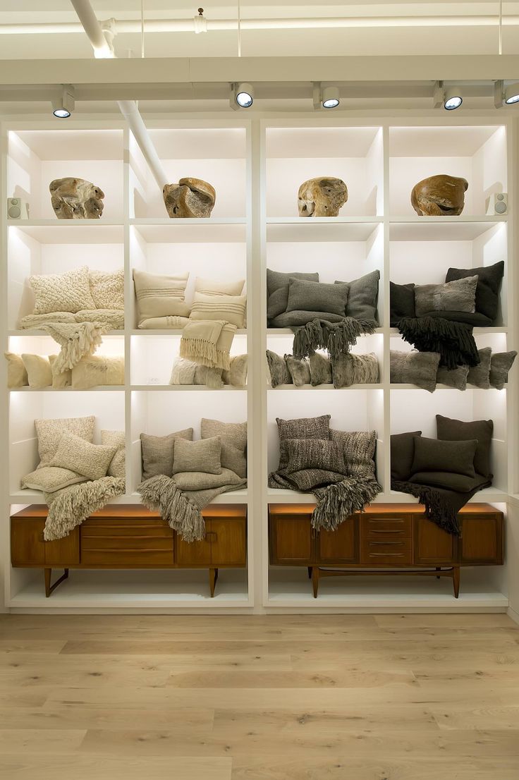 a room filled with lots of pillows and blankets on top of white shelving units