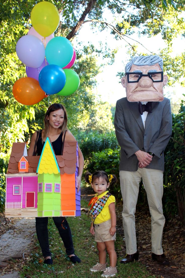 two adults and a child standing in front of a house with balloons on the head