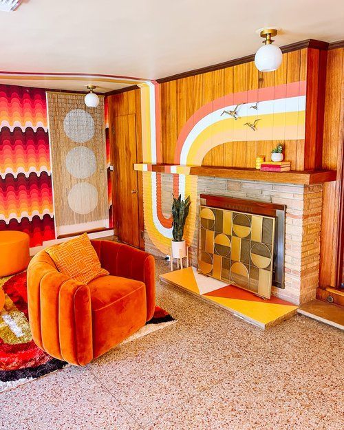 a living room with two orange chairs and a fire place in the middle of it