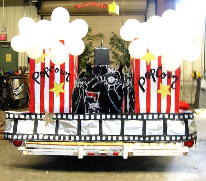 the back of a truck with balloons and decorations on it's flatbed in a warehouse