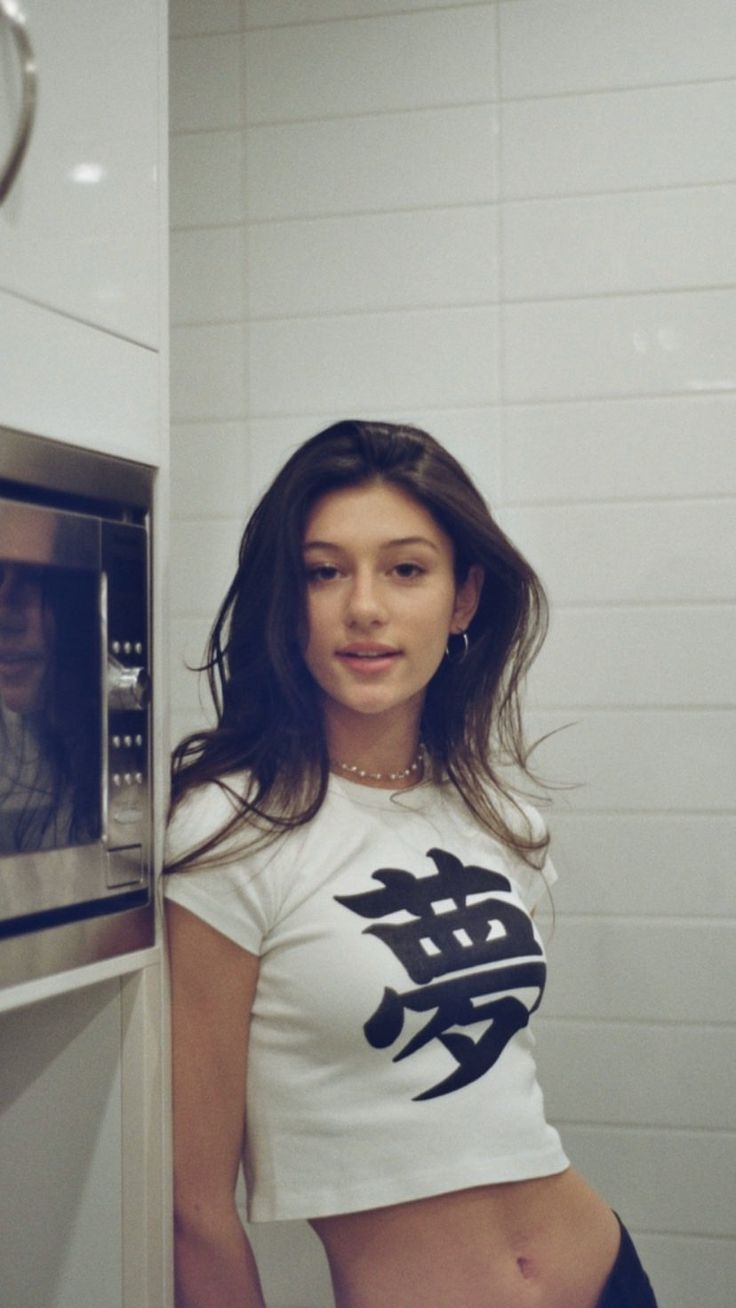 a woman standing in front of an oven with her hand on the door and looking at the camera