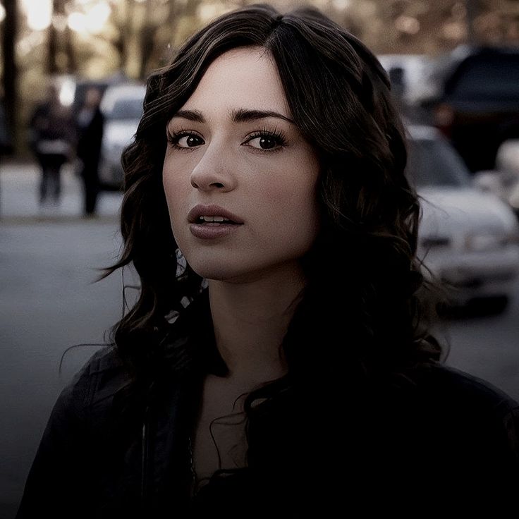 a woman is standing on the street with cars in the background