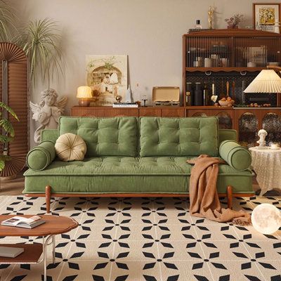 a living room with a green couch and coffee table next to it on top of a black and white checkered floor