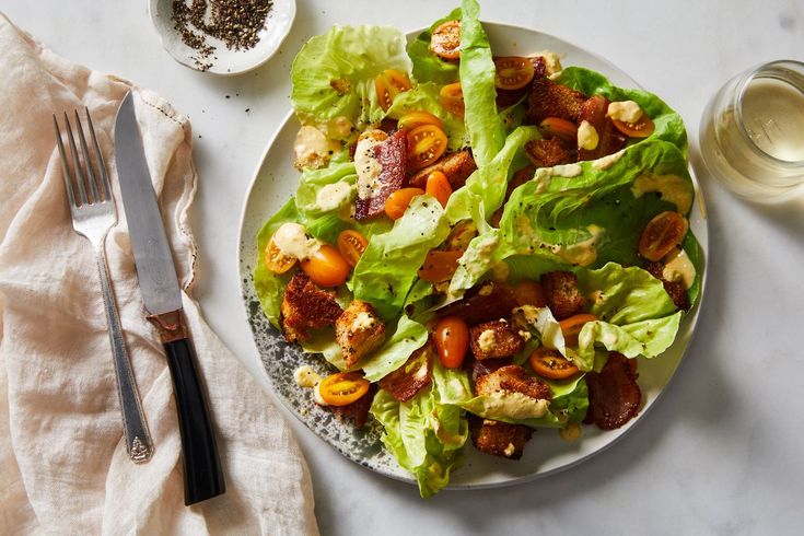 a white plate topped with lettuce and tomato salad next to a bowl of seasoning