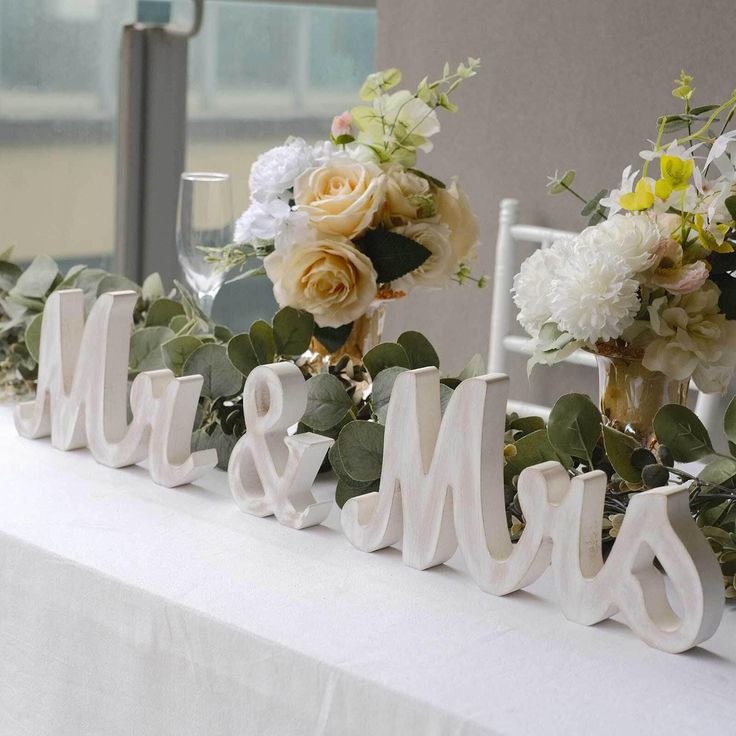 the table is set up with flowers and white letters that read mr and mrs on it