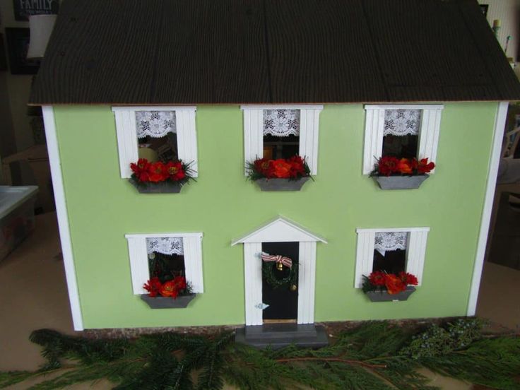 a doll house with four windows and flowers in the window boxes on the front of the house