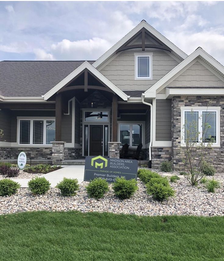 the front entrance to a home with stone and sidings on it, surrounded by green grass