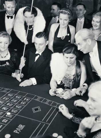 a black and white photo of people playing roulejack in front of a crowd