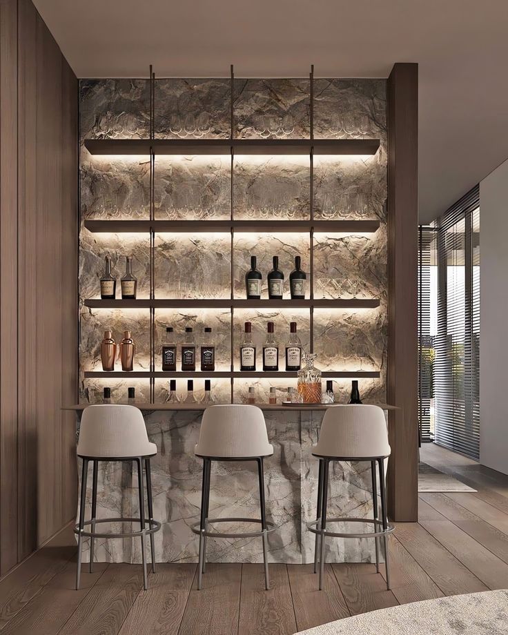 a bar with three stools in front of it and several bottles on the wall