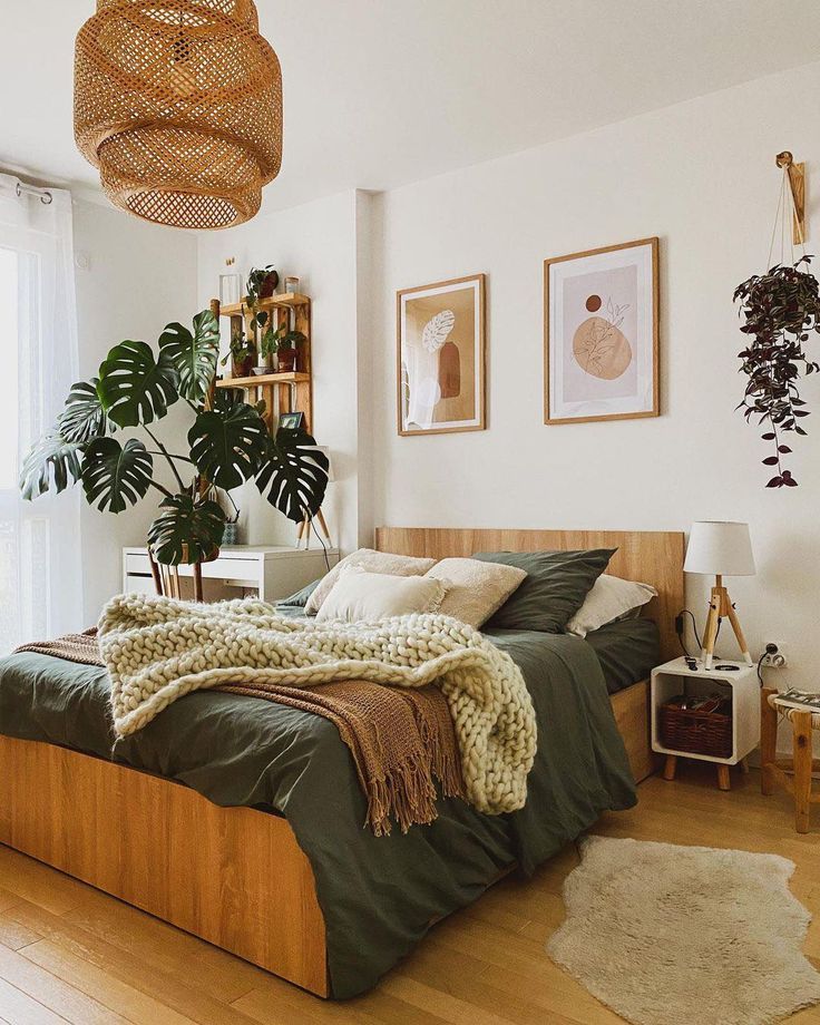 a bed room with a neatly made bed next to a large window and a potted plant