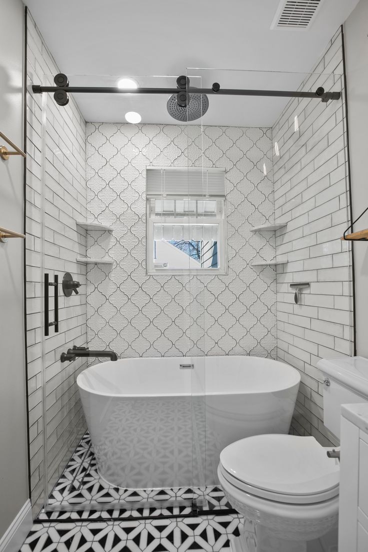 a white bathroom with black and white floor tiles on the walls, an open shower stall and a free standing tub