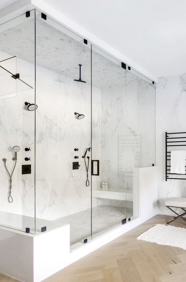 a white bathroom with glass walls and black hardware on the shower head is shown in this image