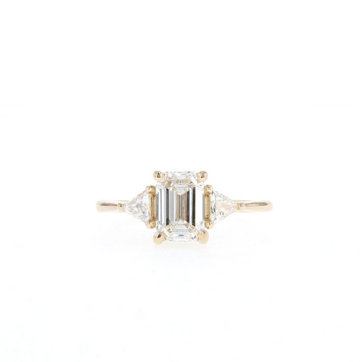 an emerald cut diamond ring with three baguets on each side and two diamonds in the middle