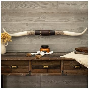 an animal's long horn is sitting on top of a wooden table next to a vase with flowers