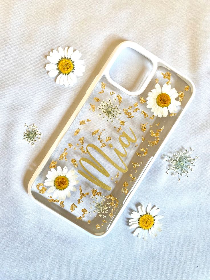 an iphone case with gold glitter and daisies