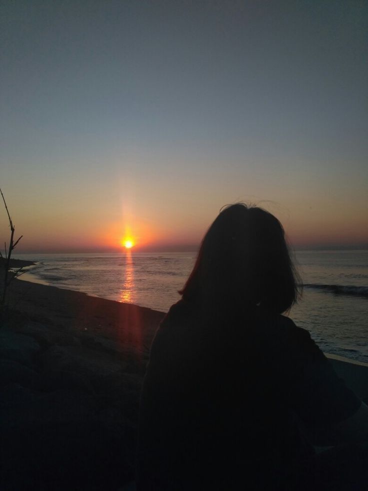 the sun is setting over the ocean and people are watching it