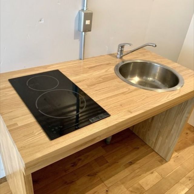 a kitchen counter with a sink and an oven on it's side, in front of a wall mounted faucet